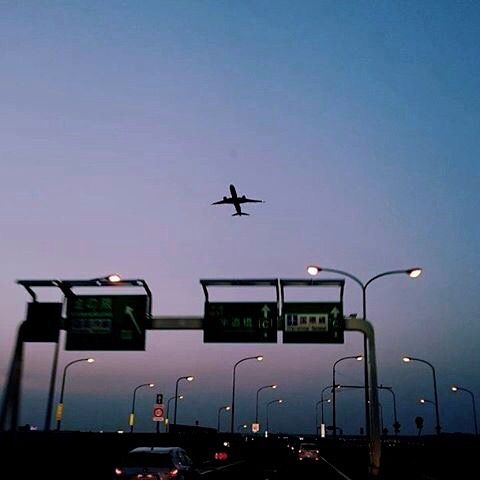 an airplane is flying over the highway at dusk