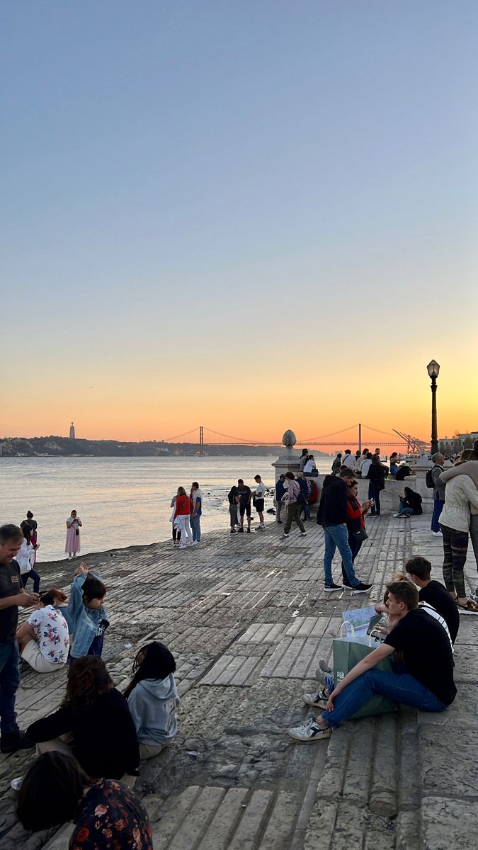 many people are sitting on the pier at sunset