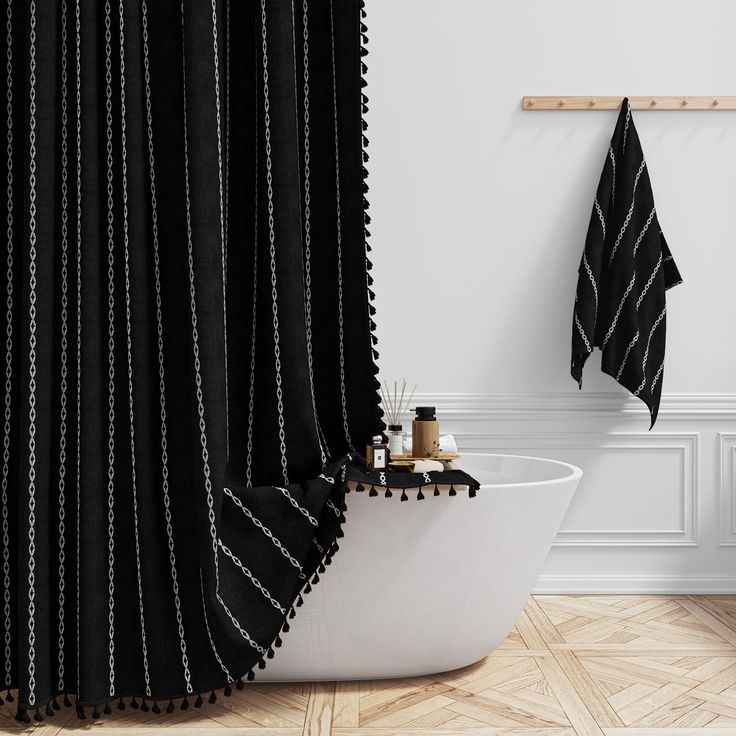 a black and white bathroom with a bathtub, shower curtain and towel hanging on the wall