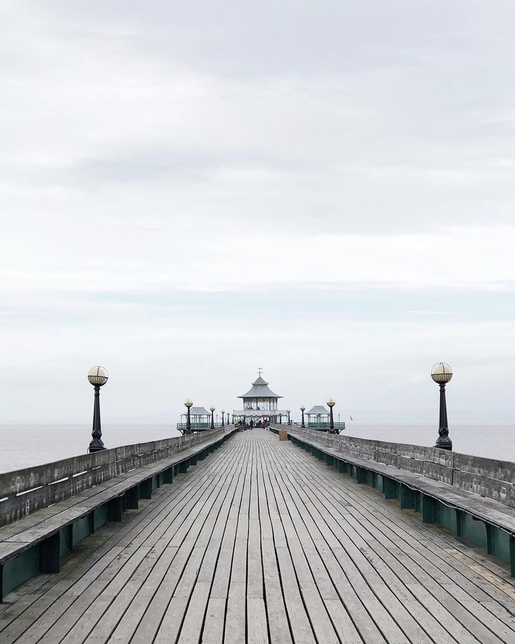 a wooden pier with lights on it and the ocean in the background at an angle