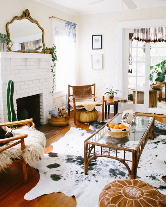 a living room filled with furniture and a fire place under a mirror on the wall