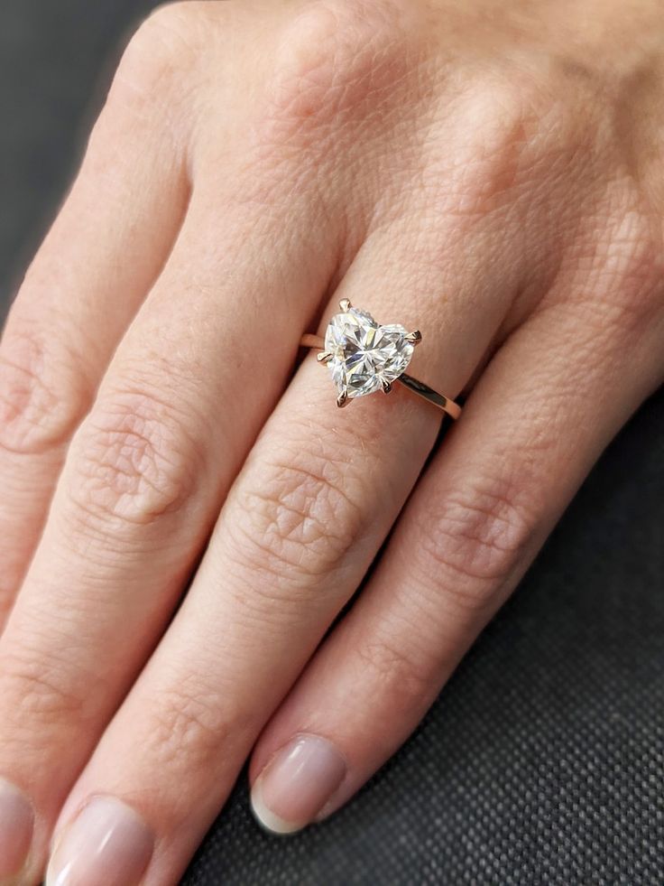 a woman's hand with a diamond ring on her left hand, showing the center stone