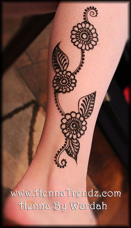 a woman's foot with black henna tattoos on her leg and feet,