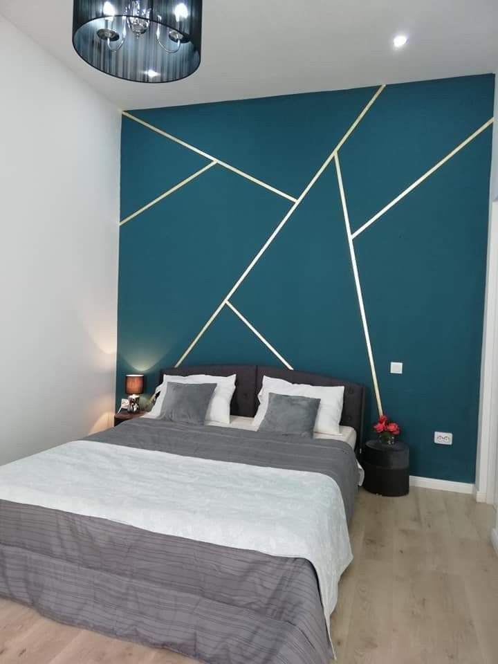 a large bed sitting in a bedroom next to a wall with gold lines on it