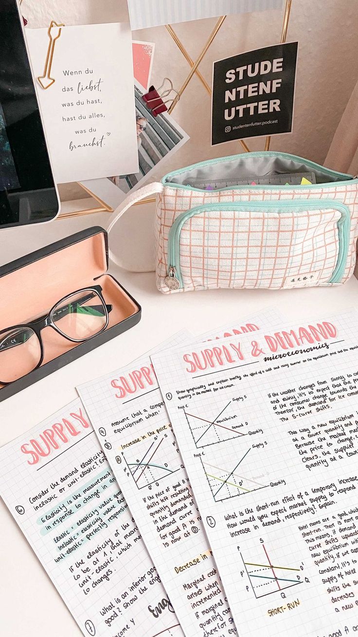 some papers and glasses on a desk with a computer monitor, pen holder and other items