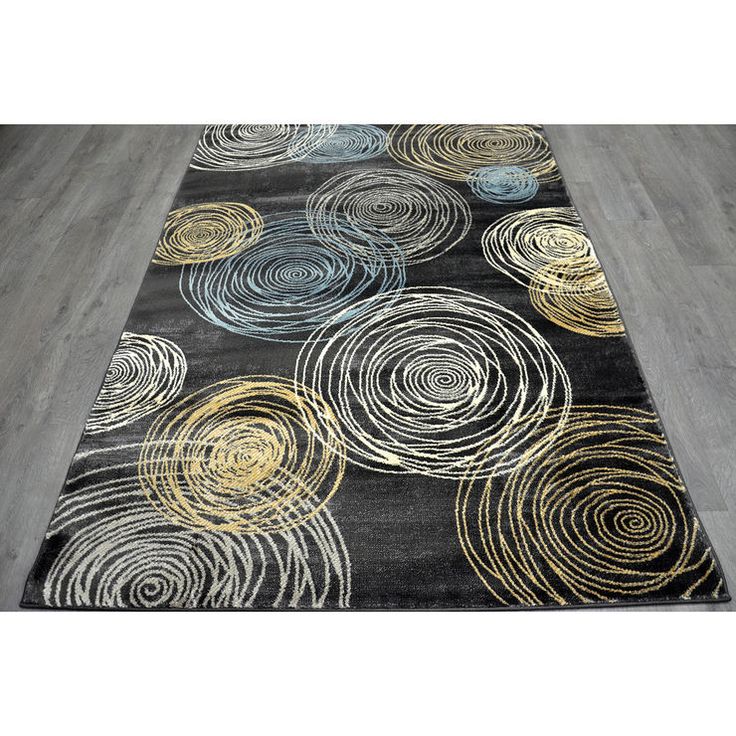 a black rug with gold and silver circles on the floor in front of a wooden floor