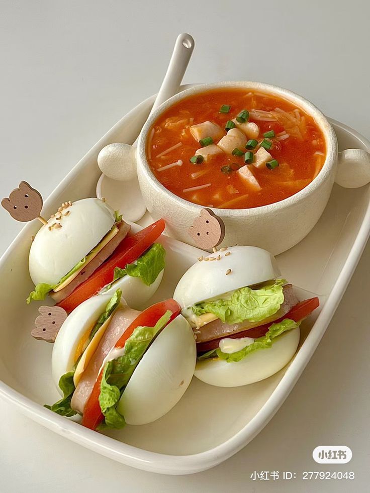 there is a plate with sandwiches and soup on it, along with an egg in the shape of a mouse