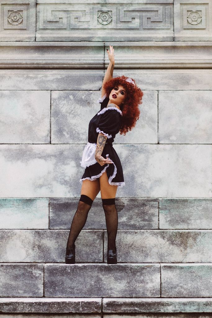 a woman in black and white dress standing on steps with her arms up to the sky