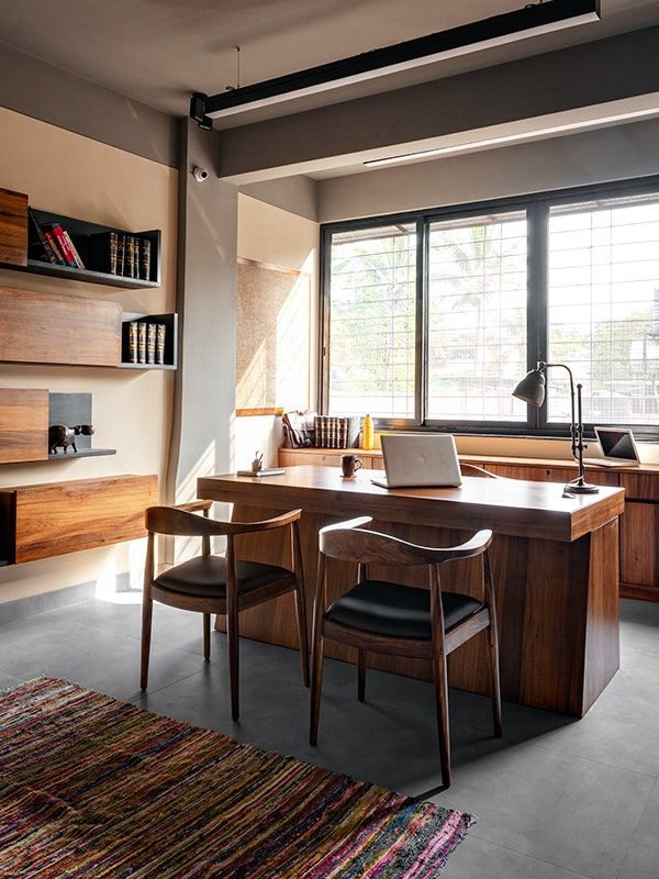 a desk with two chairs and a laptop on it in front of a large window