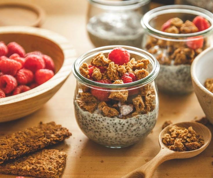 various bowls and spoons filled with granola, raspberries and oatmeal