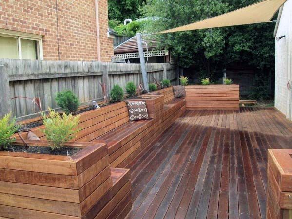 a wooden deck with planters on it and an umbrella in the back ground area