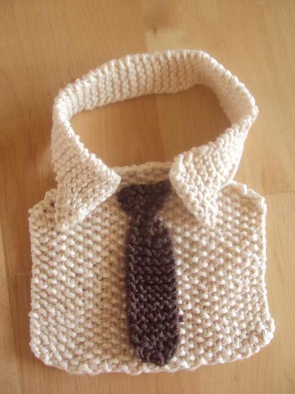 a knitted sweater with a tie on top of a wooden table next to a bag