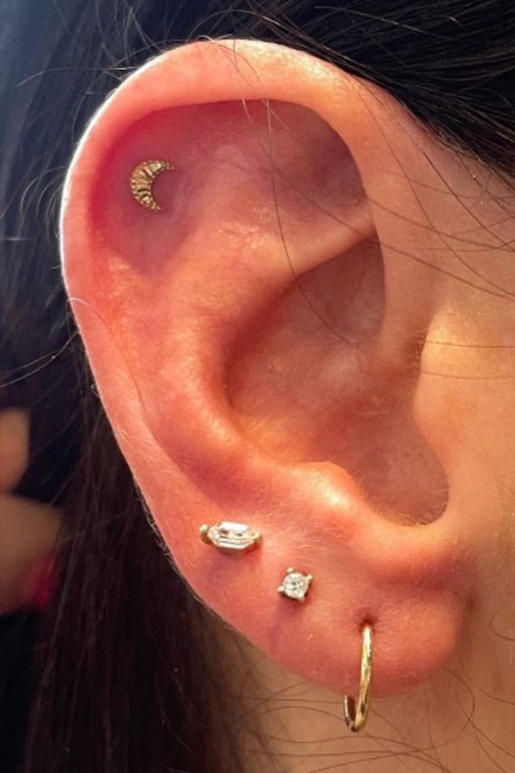 a woman's ear with three different piercings