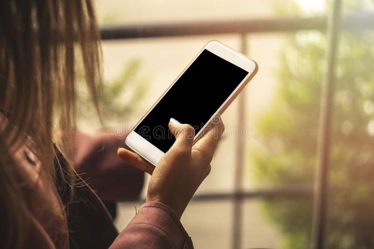 a woman holding a smart phone in her hand and looking at the screen with a serious look on her face