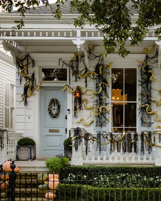 a house decorated for halloween with decorations on the front door and windows in black, gold and white