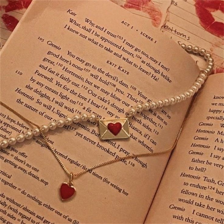 a book with two necklaces on top of it and an open book in the background