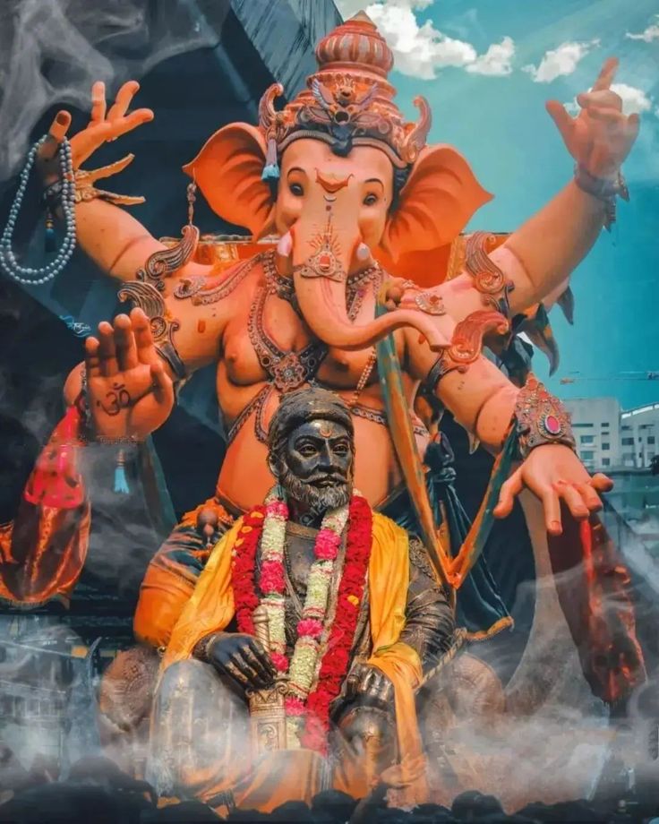 an elephant statue sitting on top of a cloud covered ground next to a man in costume