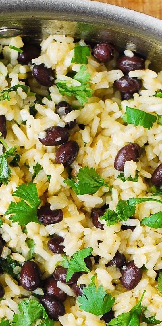 rice with beans and cilantro in a silver bowl on a wooden table top