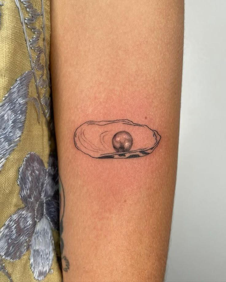 a woman's arm with a tattoo that has an egg in the shell on it