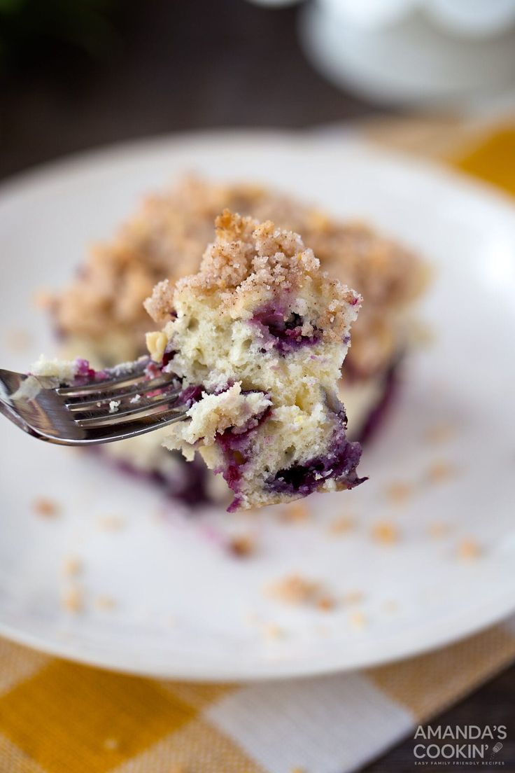 a piece of blueberry crumb cake on a white plate with a fork in it