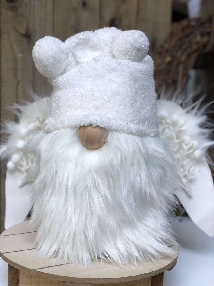 a white stuffed animal wearing a hat on top of a wooden table