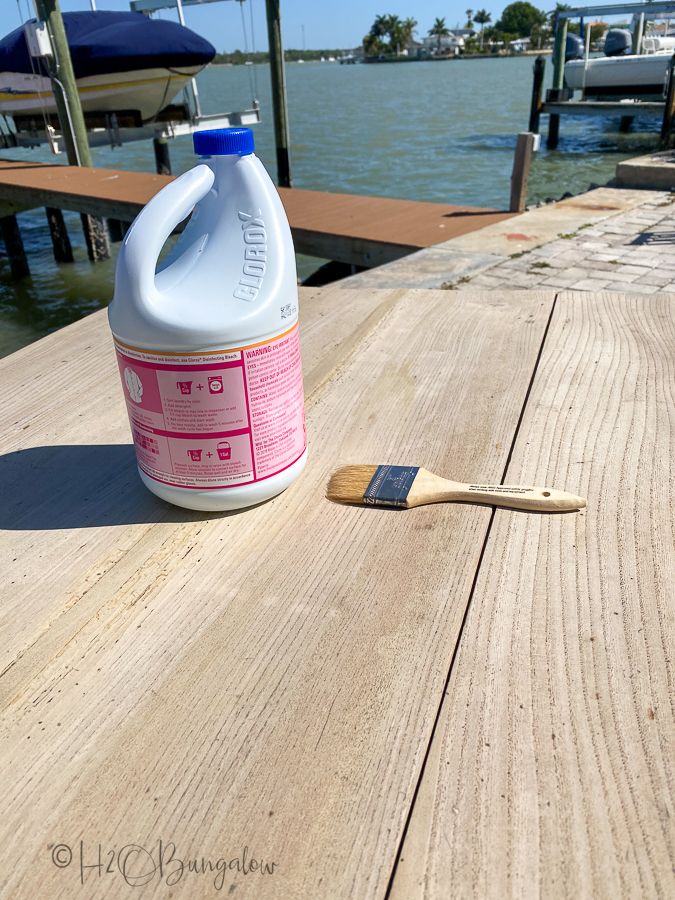 a bottle of cleaner next to a brush on a wooden dock