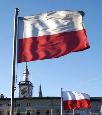 two flags flying next to each other in front of a building with a clock tower