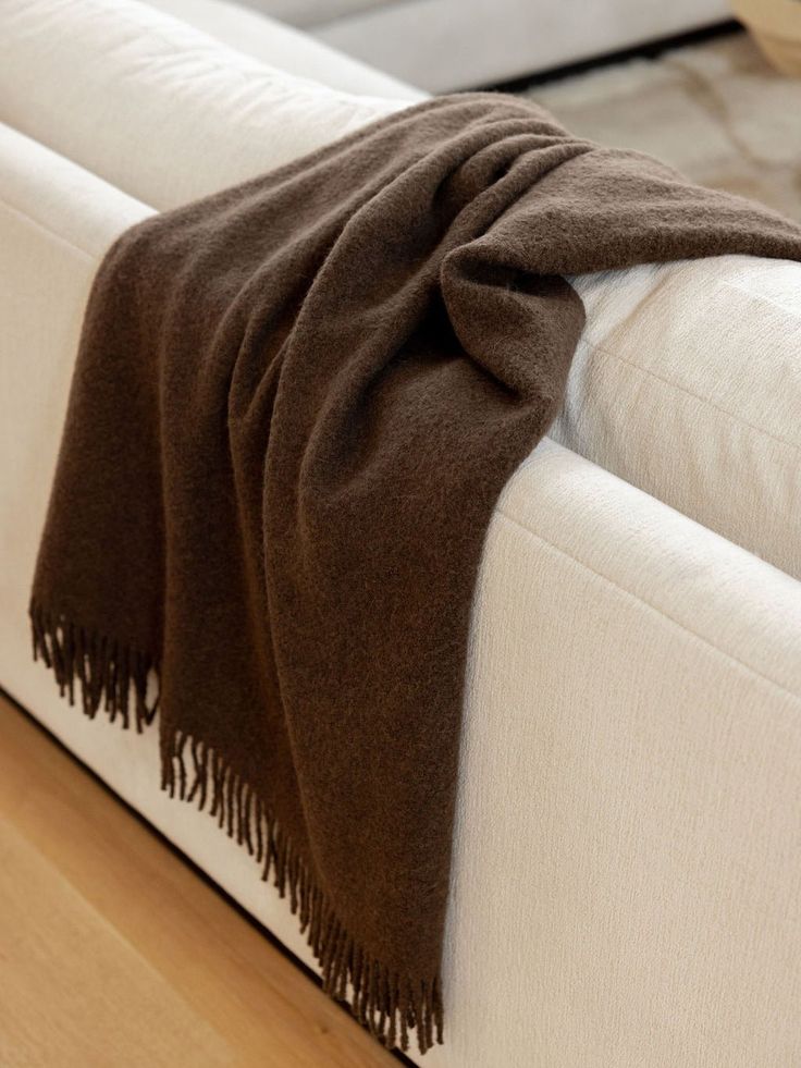 a white couch with a brown blanket on it