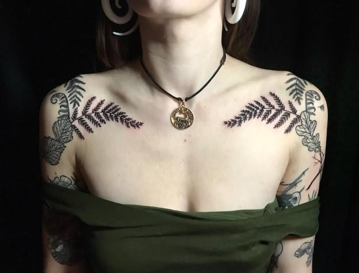 a woman with tattoos on her chest wearing a green dress and large hoop earring