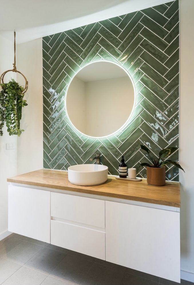 a bathroom with a round mirror on the wall next to a sink and potted plants