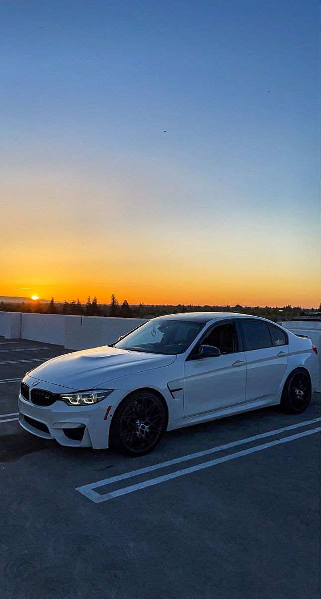 a white car parked in a parking lot at sunset