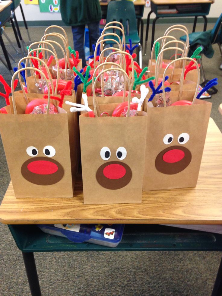 brown paper bags with reindeer noses and nose on them sitting on a table in a classroom