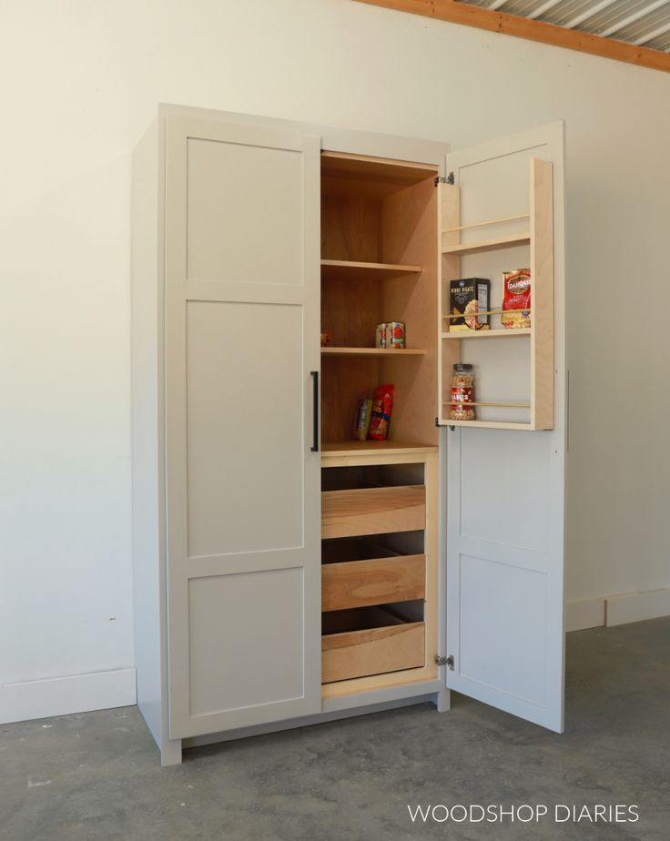 an open cabinet with shelves and drawers in a room that is painted white, showing the contents inside