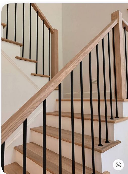 a wooden stair case with black handrails in a home's entryway