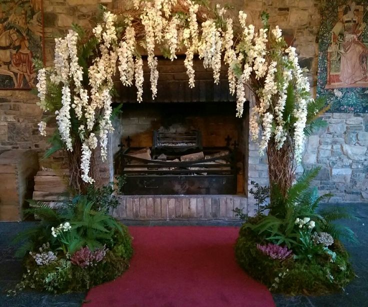 a fireplace with flowers and greenery on the mantle