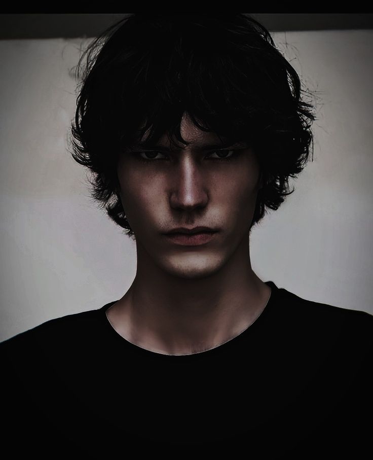 a young man with dark hair is staring at the camera while wearing a black t - shirt