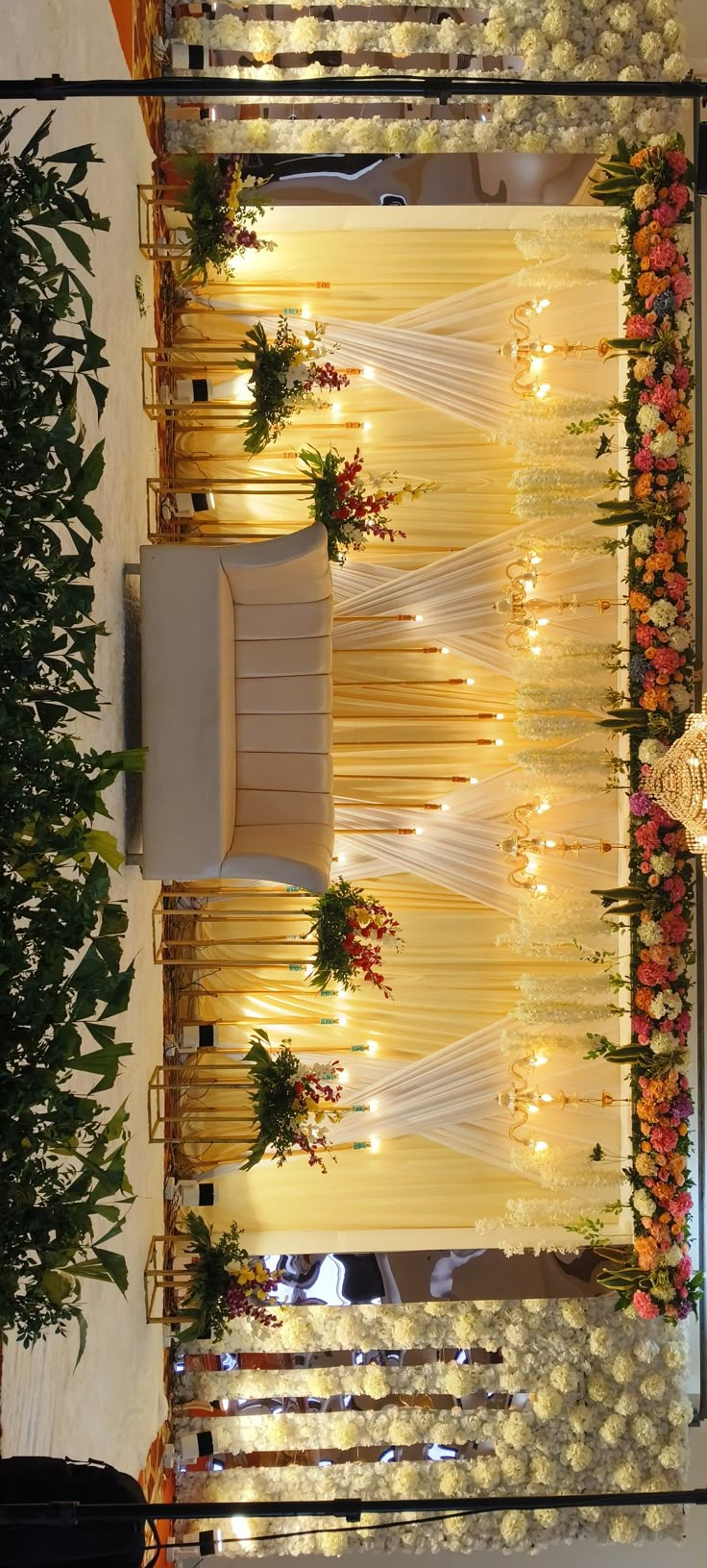 an arrangement of flowers and lights decorates the wall in this wedding ceremony venue at night