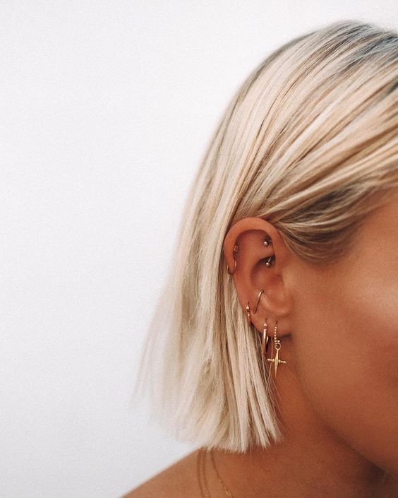 a woman with blonde hair and piercings on her ear