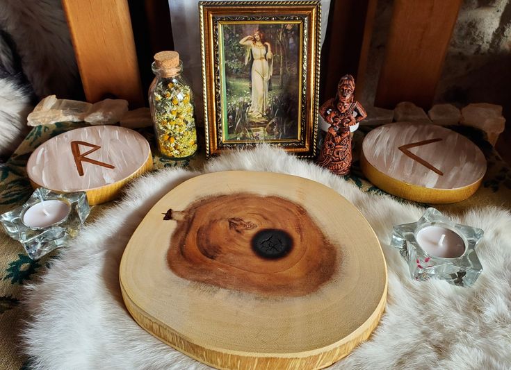 a wooden table topped with lots of different types of items next to a painting and candles