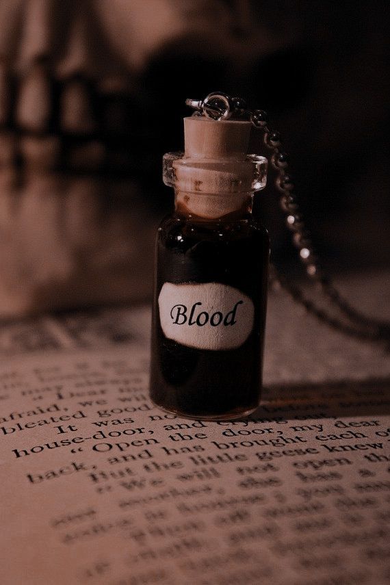 a bottle that is sitting on top of an open book with the word blood in it