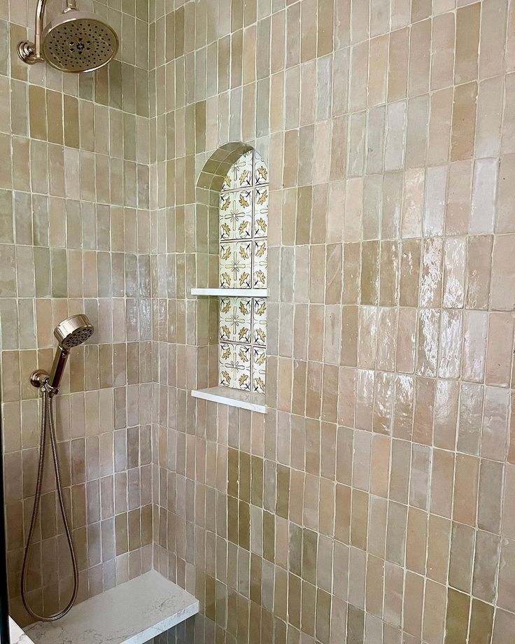 a bathroom with a shower head, window and tiled wall in the shower stall area