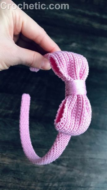 a hand holding a pink crocheted hair tie