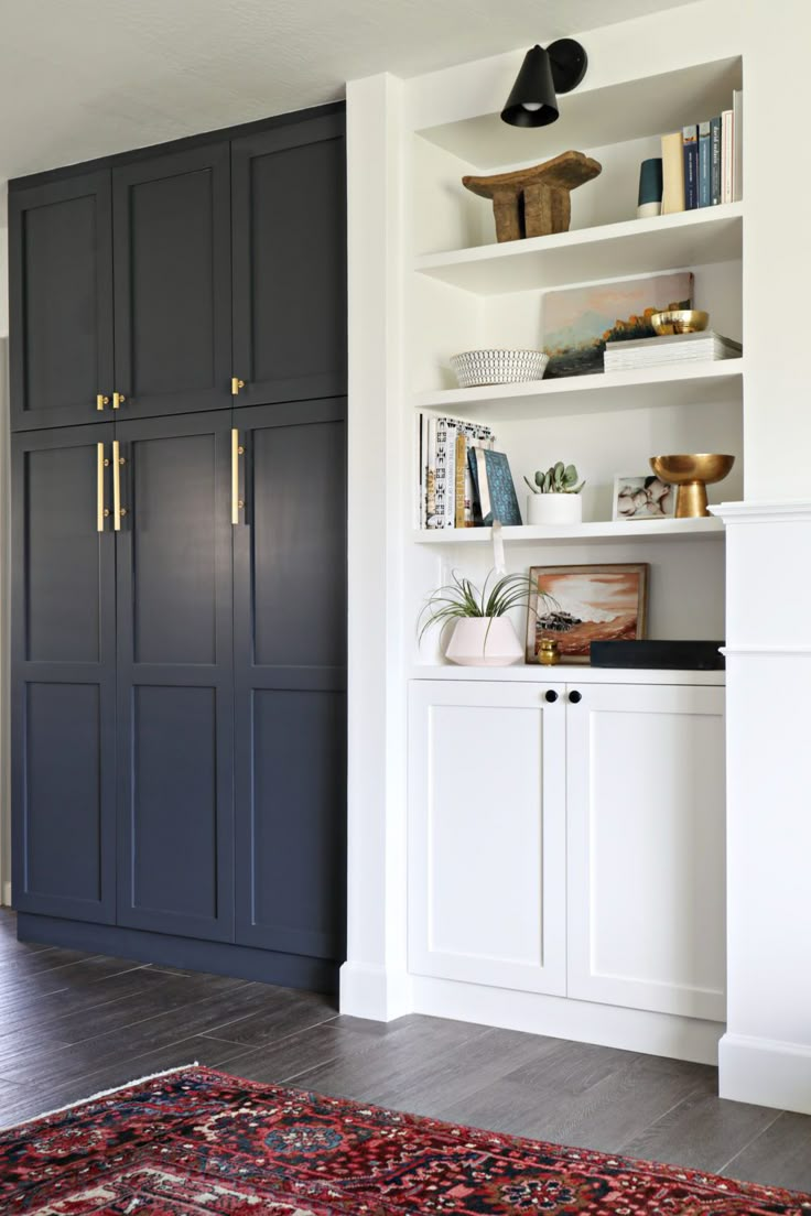 an image of a room with white cabinets and black cupboards on the wall, along with a red rug