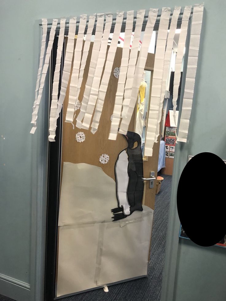 a penguin is standing on the ground in front of a mirror with clothes hanging from it