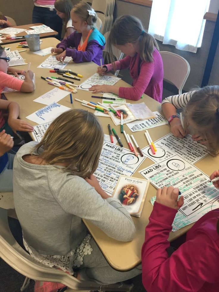 several children sitting at a table doing crafts