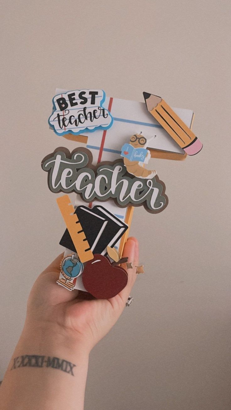 a person holding up a teacher sign made out of different types of magnets and paper