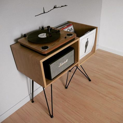 an old record player is sitting on top of a wooden side table in front of a white wall