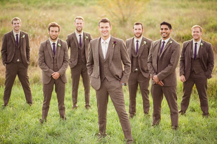 a group of men standing next to each other on top of a lush green field