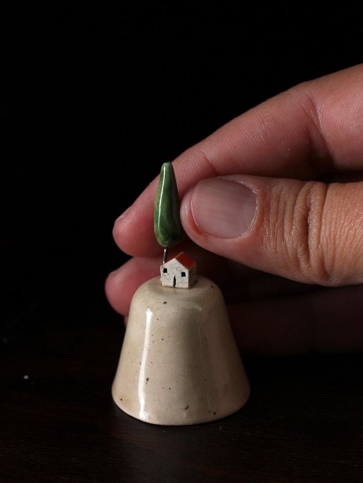 a miniature house on top of a bell with a small tree growing out of it