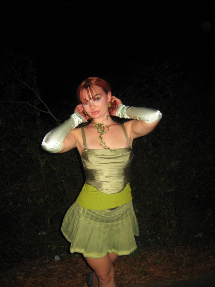 a woman in a green dress is posing for the camera with her hands on her head